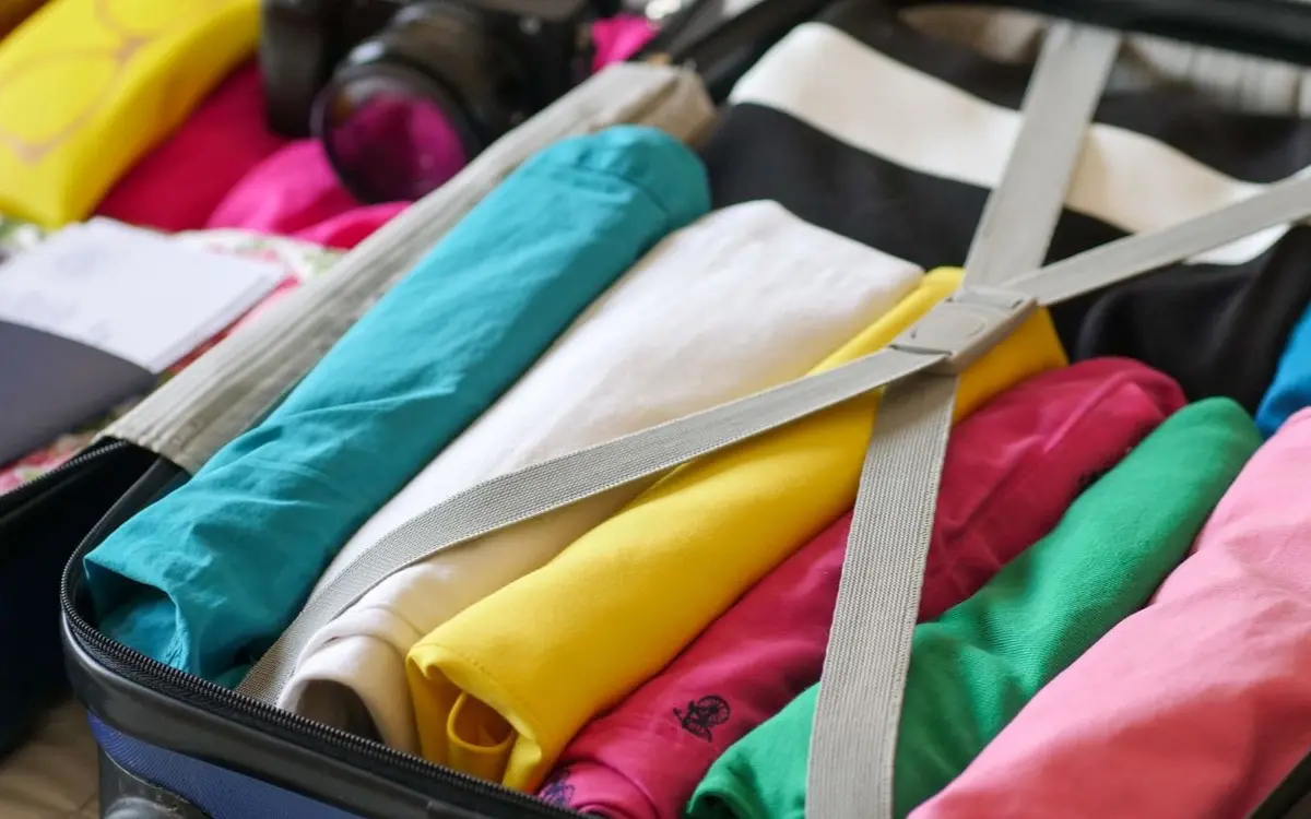 Open suitcase neatly packed with colorful clothes and travel