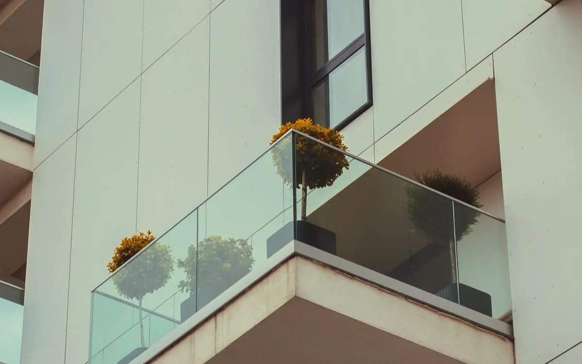 A modern apartment building's glass balconies with potted pl